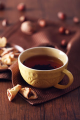 Cup of tea with autumn decor on wooden table.