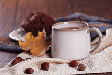 Cup of tea with autumn decor on wooden table.