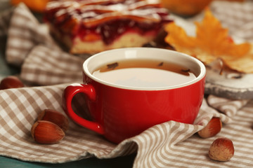 Cup of tea with autumn decor on wooden table.