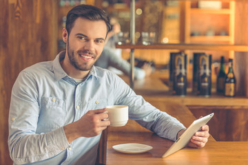 Young businessman with gadget at cafe