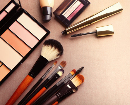 Decorative cosmetics and accessories for makeup on beige background