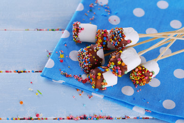 Tasty marshmallows with chocolate on sticks, close up