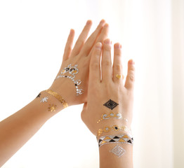 Silver and golden flash tattoo on female hands over white background