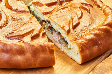 Cut pie with chicken and mushrooms on a wooden table