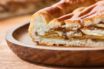 A piece of pie with a filling of apples on a wooden plate