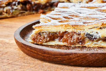 A piece of cake stuffed with dried fruits on wooden plate