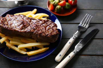 Grilled steak with french fries and vegetables, closeup