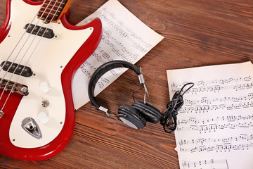 Naklejka premium Electric guitar with headphones and notes on wooden background