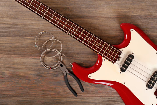Electric guitar with pliers and strings on wooden background