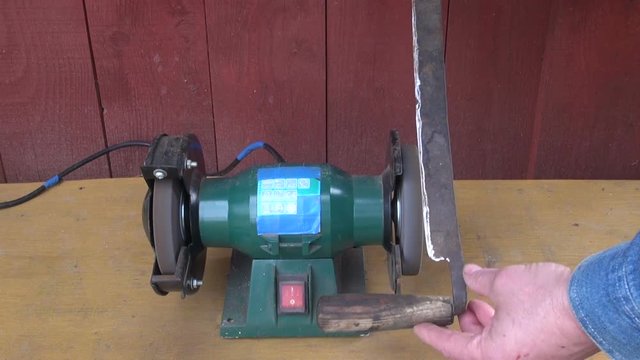 Man farmer sharpening bark peeler with electrical tool sharpener