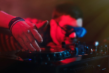 DJ playing music at mixer on colorful blurred background