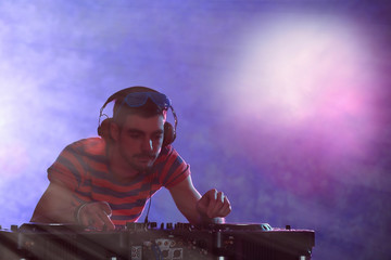 DJ playing music at mixer on colorful blurred background