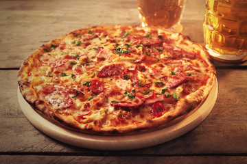 Delicious pizza  and glasses of beer are on wooden table, close up