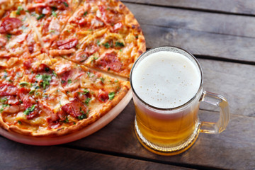 Tasty pizza and glass of beer are on wooden table, close up