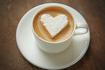 Cup of coffee with marshmallow on wooden table