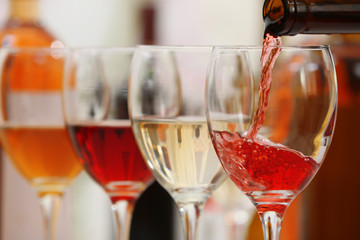 Red wine pouring into glasses, closeup