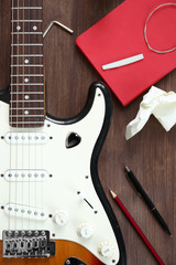 Fototapeta premium Guitar with notebook on wooden table closeup