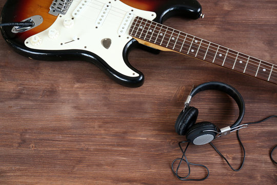 Guitar with headphones on wooden surface closeup