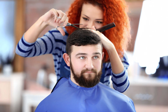 Professional hairdresser making new haircut  her handsome client