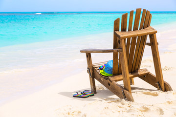 Wooden beach chair with hat and slippers at beach cost, summer holiday concept