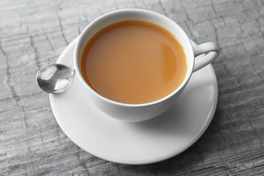 Cup of tea with milk on wooden background