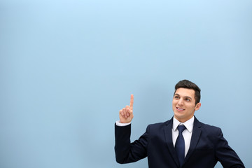 Attractive young man in a suit against light blue wall