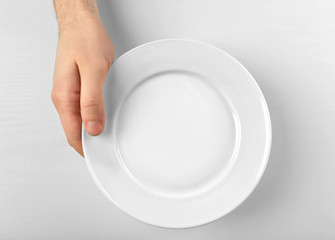 Male hand holding white plate, isolated on white