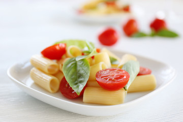Boiled rigatoni pasta with fresh tomatoes and basil on white plate