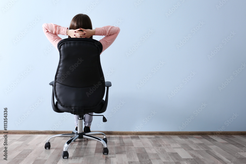 Wall mural Woman sitting back on the office chair indoors