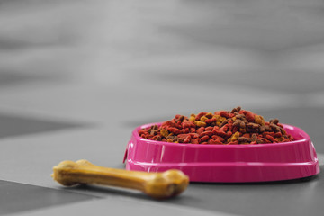Pet food in a pink bowl on a floor.