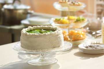 Fresh homemade cake with sliced kiwi on a glass plate.