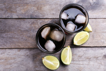 Glasses of soda water and sliced lime on wooden table, top view