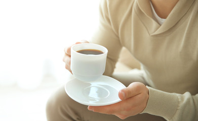 Man holding cup of coffee in hands, close up