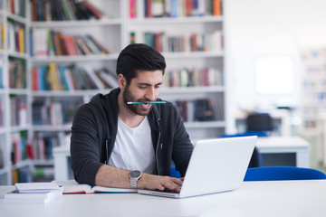 student in school library using laptop for research
