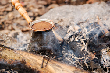 Hot coffee prepared in turk on open fire. Closeup.