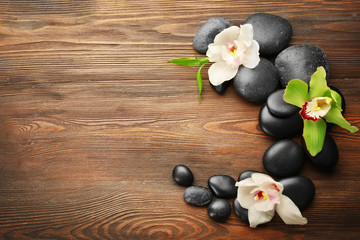 Beautiful spa composition with stones and orchids on wooden background