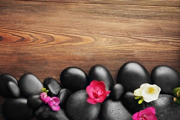Beautiful spa composition with stones and flowers on wooden background