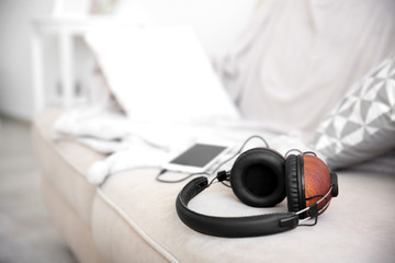 Stylish headphones and mobile phone on couch
