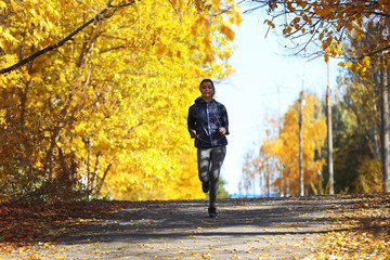 Obraz premium Young beautiful woman running in autumn park and listening to music with headphones.