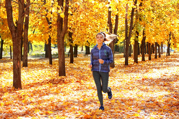 Young beautiful woman jogging in autumn park