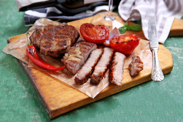 Roasted beef fillet and vegetables on cutting board, on wooden background