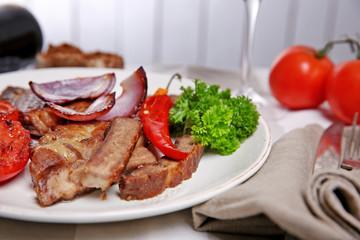 Roasted beef fillet and grilled vegetables on plate, on wooden background
