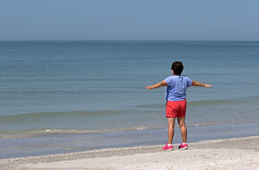 Senior woman stretching and exercising on a sunny morning on a Gulf Coast beach.