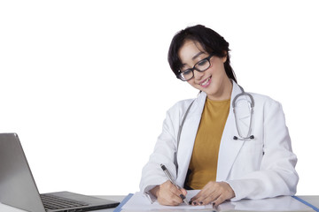 Beautiful female doctor writes on desk