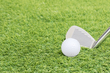 Golf ball and golf club on green grass