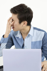 Stressed young man sitting at his desk in front of computer in office