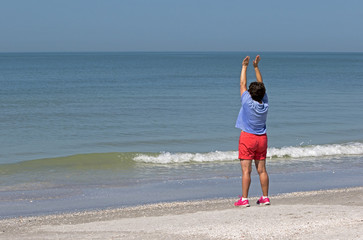 Fototapeta na wymiar Senior woman stretching and exercising on a sunny morning on a Gulf Coast beach.