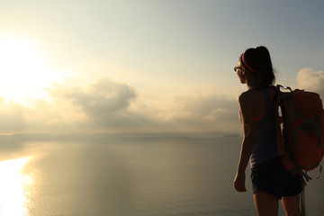  young woman backpacker enjoy the view at sunrise seaside mountain peak