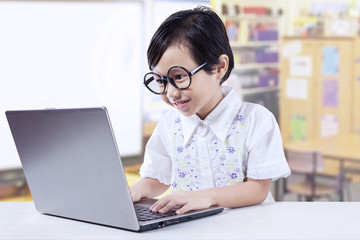 Little Girl Wearing Glasses And Using Laptop