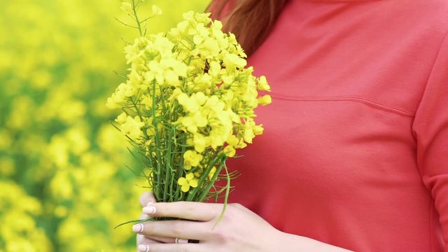 Close up girl smelling rape bouquet and smiling. Slow motion